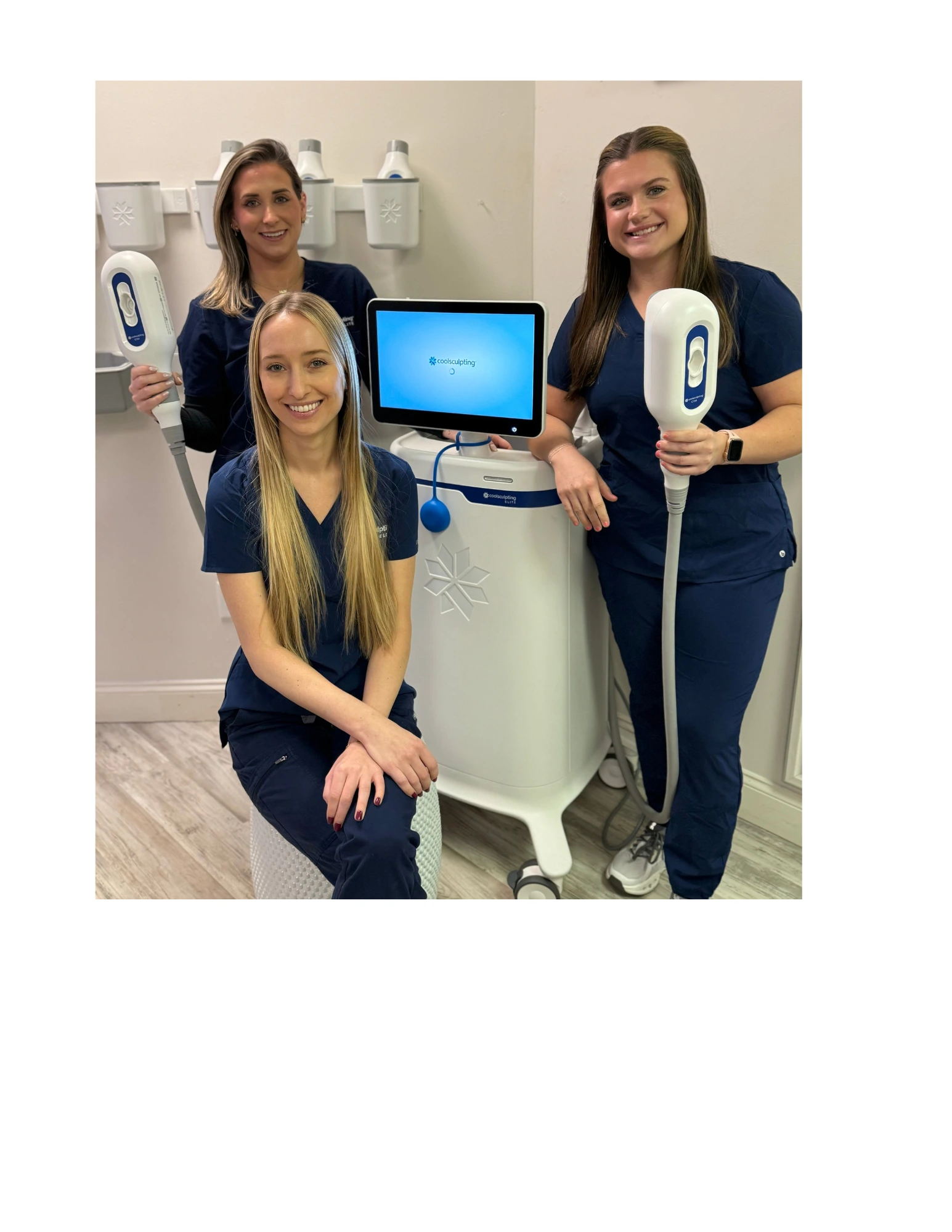 Three Thrive Med Spa providers demonstrating CoolSculpting equipment with handheld applicators in a clinical treatment room